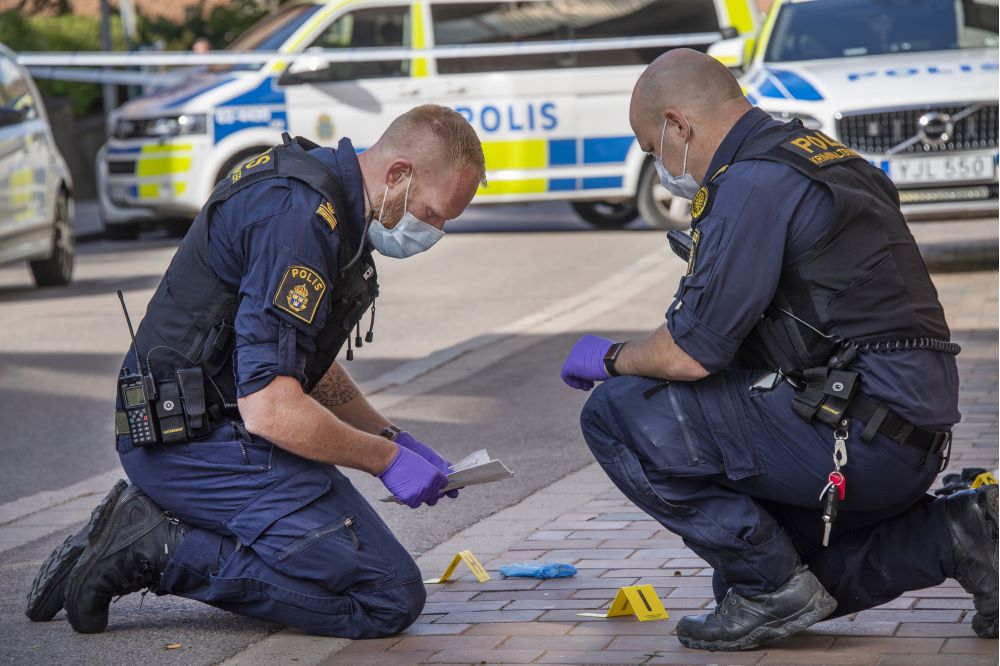 Poliser gör en teknisk undersökning på marken.