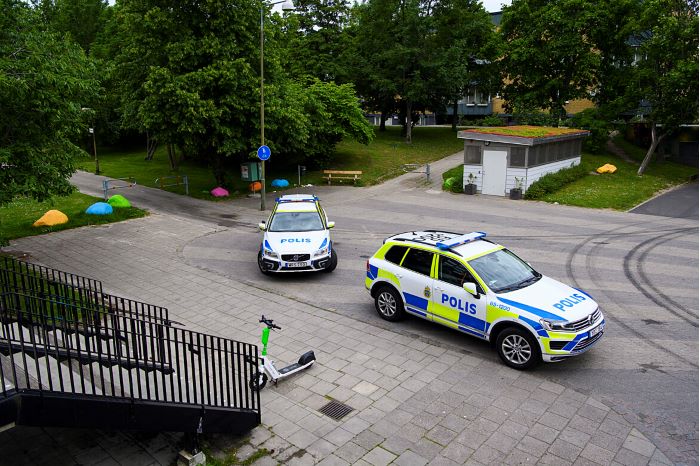 Två bilar på en gata i ett bostadsområde med flerfamiljshus, bilden är tagen uppifrån