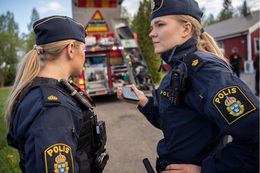 Poliser som tittar på varandra med räddningstjänsten i bakgrunden