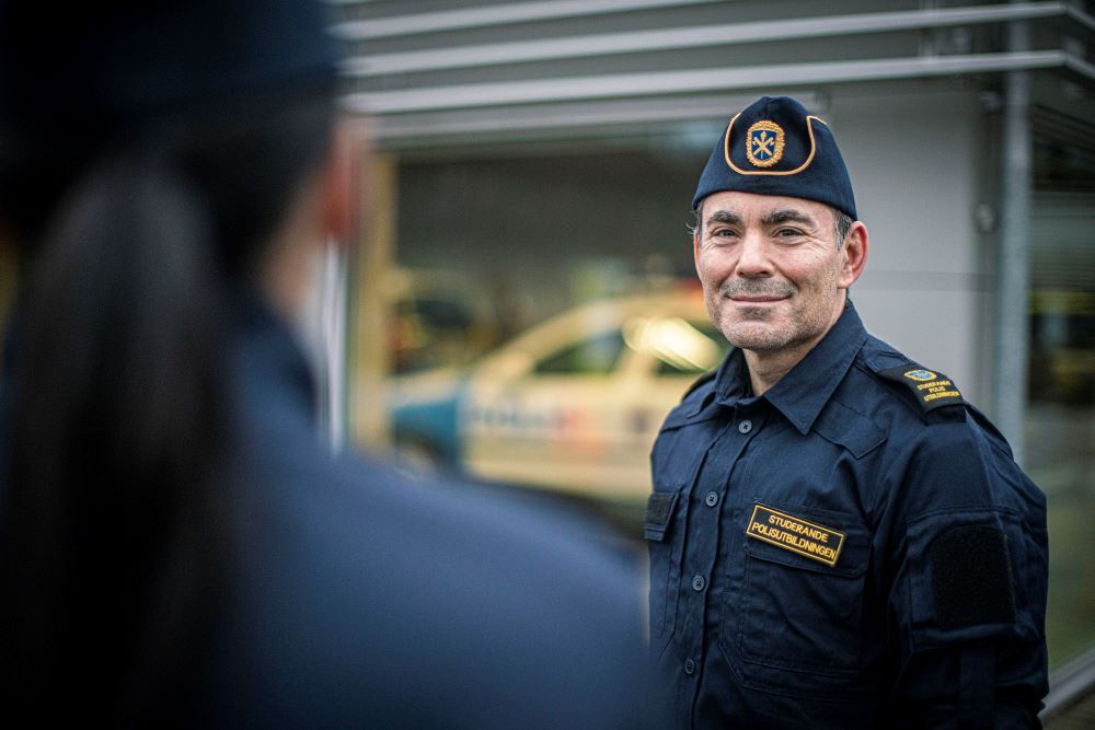 Polisen Jon står framför en person som man bara ser bakhuvudet på.