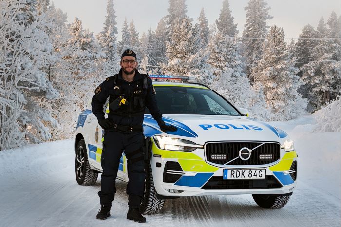 polisman står framför polisbil med snö på marken