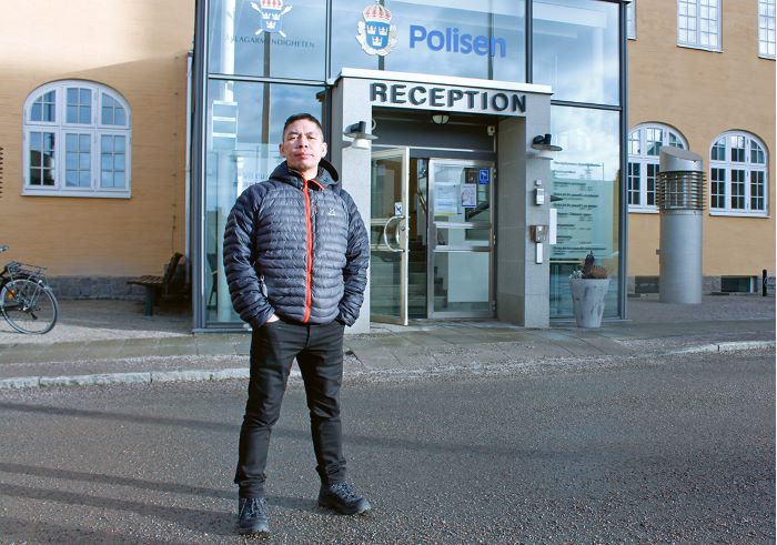 Polisanställd står utanför en polisstation. Foto.