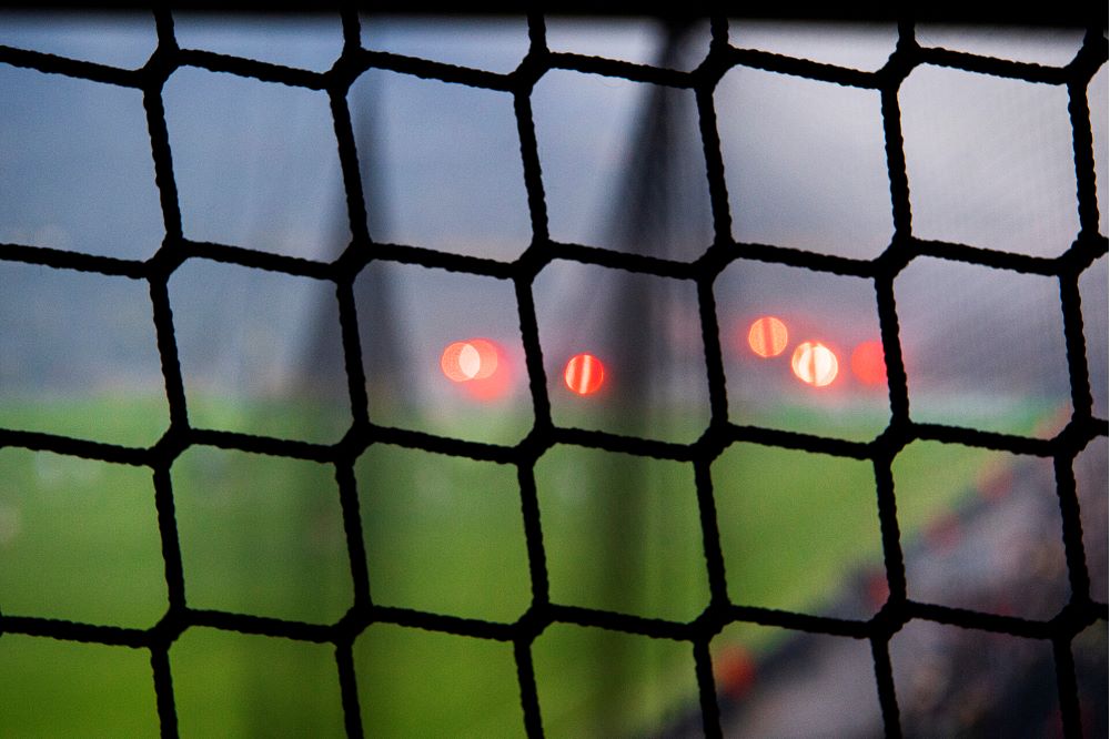 Närbild på fotbollsmålsnät och bengaler i bakgrunden