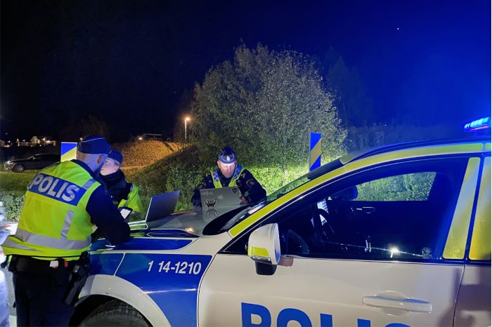 Poliser som står lutade mot polisbil