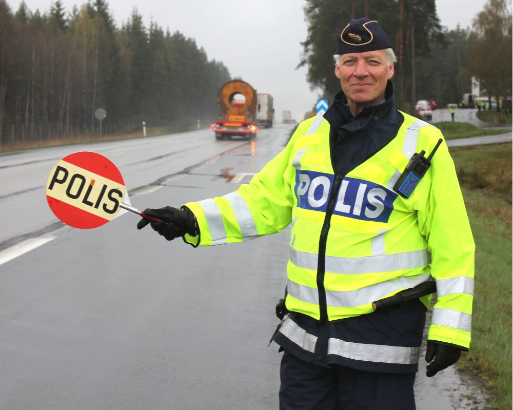 Polisman stoppar bilar för kontroll vid trafikkontrollplats.