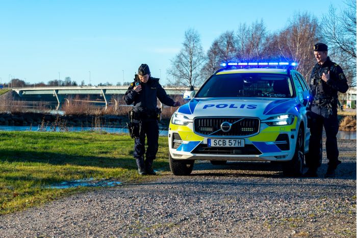 Poliser som står bredvid polisbil. De ser ut att vara på väg att köra från platsen.