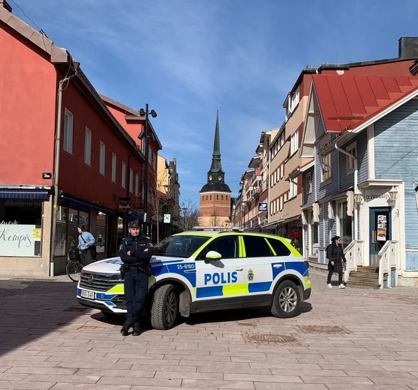 Polisbil parkerad på ett torg med polisman framöver