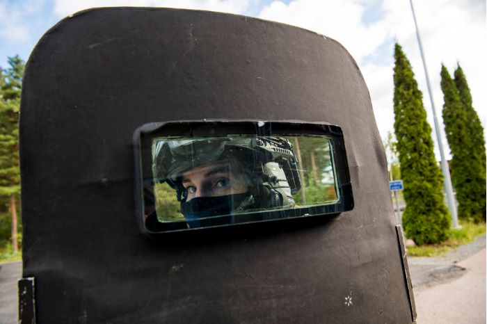 Jenny utrustad i sin insatshjälm och skydd för mun och näsa reflekteras i en spegel. Foto.