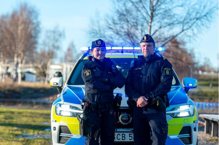 Poliser som står framför polisbil. Höst