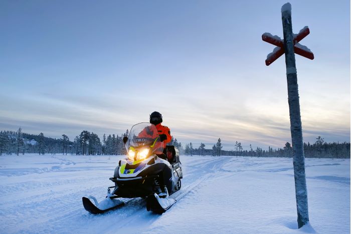 polis på snöskoter med ledkryss på sidan av skotern.