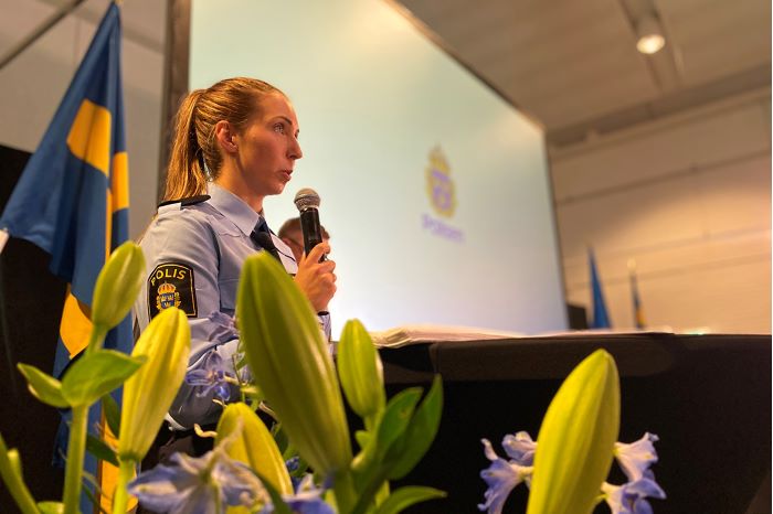 En kvinnlig polisaspirant håller tal under ceremonin.