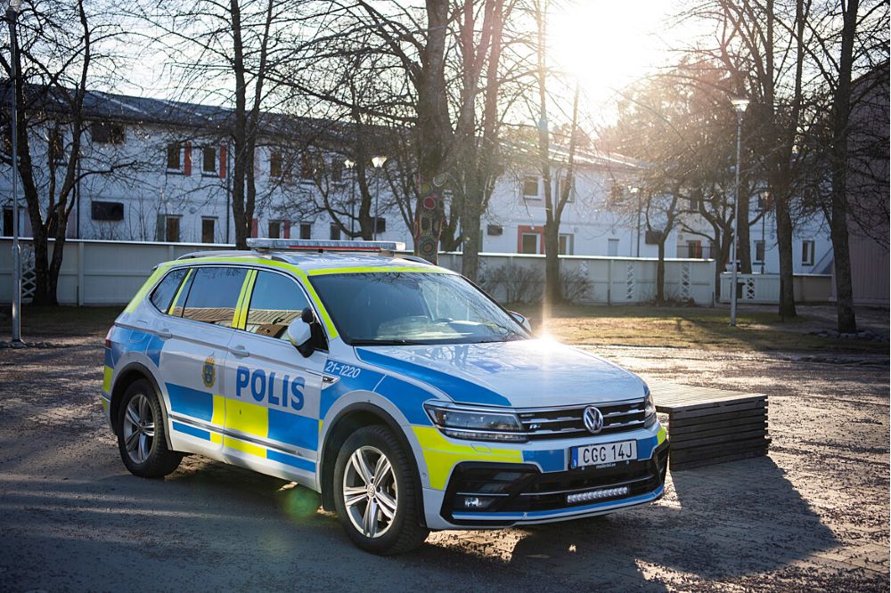 Polisbild framför staket och vitt hus i bakgrunden