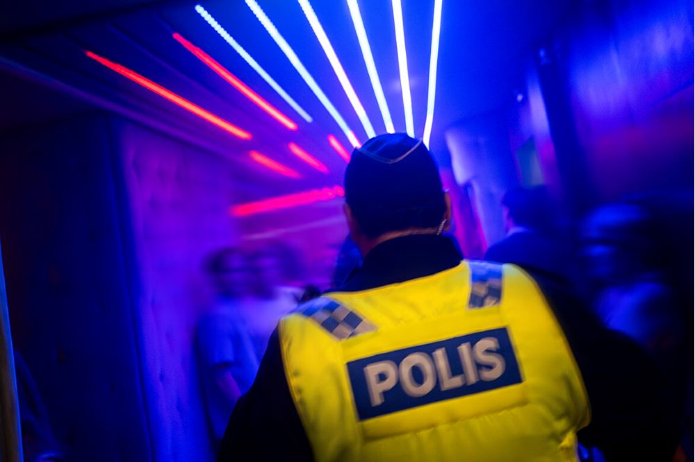 Polis med gul väst i ett mörkt rum