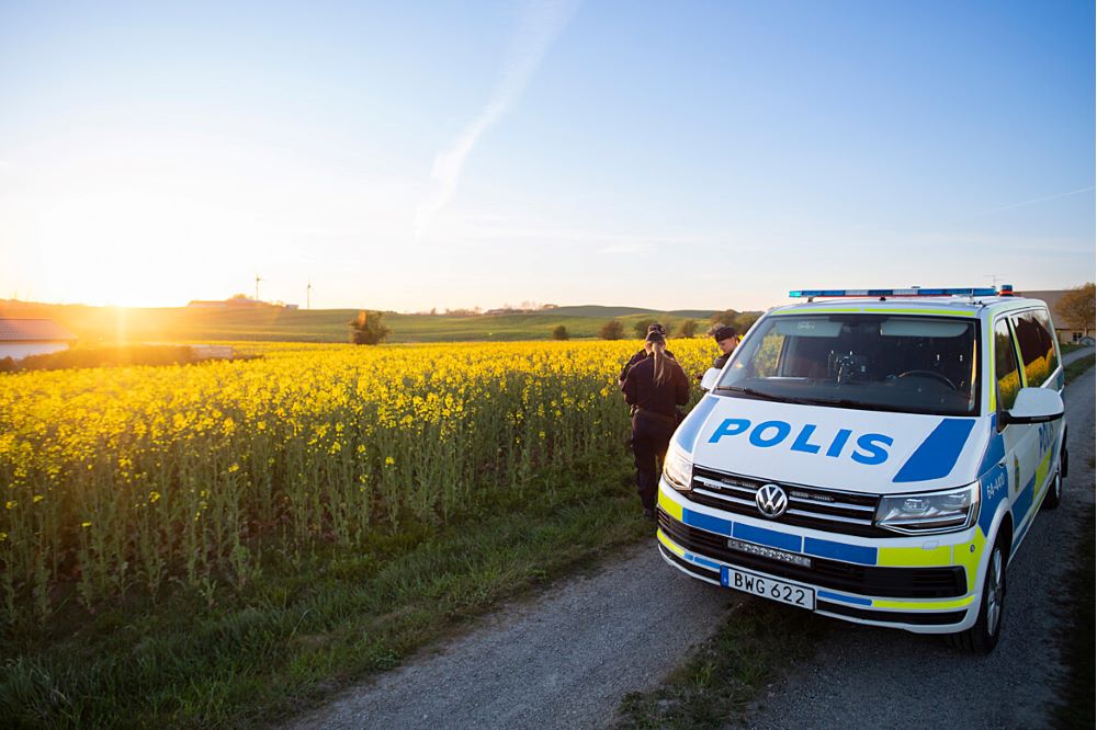 Polisbil intill ett gult rapsfält