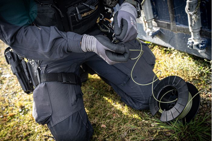 Bombtekniker som har händerna kring en sladd