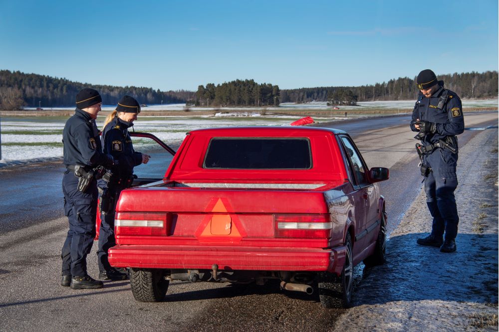 Tre uniformerade poliser kontrollerar en röd A-traktor.