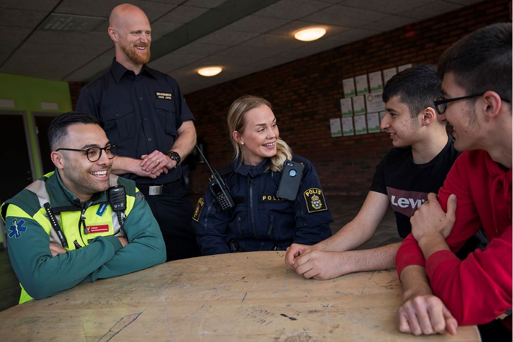 Polis, ambulanspersonal och räddningstjänst träffar två unga män.