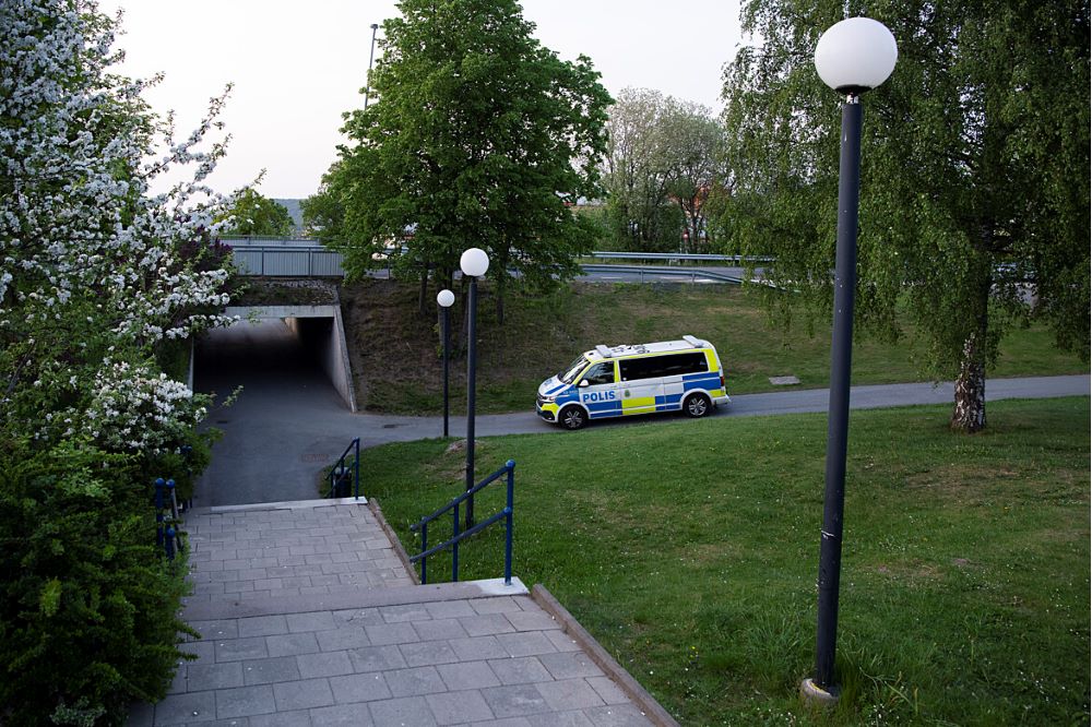 En polisbuss kör i skymningen inne i ett bostadsområde.