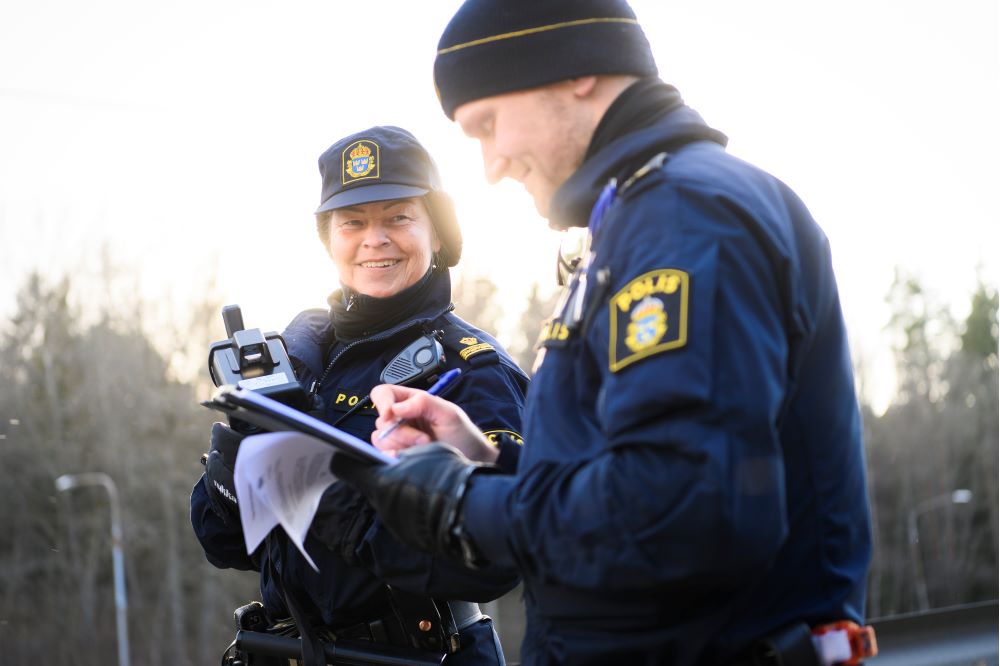 Två poliser. En man och en kvinna i vinteruniform ler.