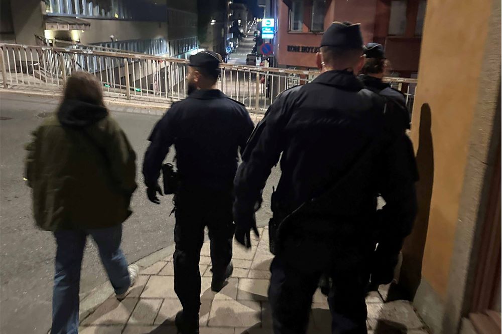 Foto på fyra polisanställda som går längst röda tegelbyggnader i Stockholms innerstad.