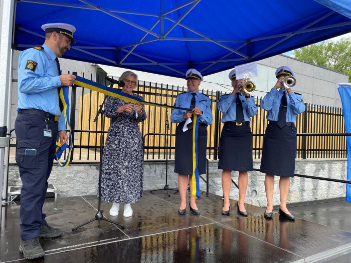 Fyra polisernpå en scen. En civilklädd kvinna klipper invigningsband.